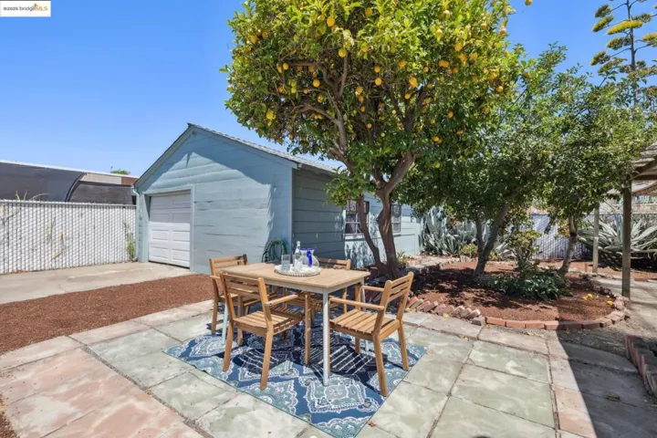 View of patio / terrace featuring outdoor dining area, an outbuilding, driveway, and a garage