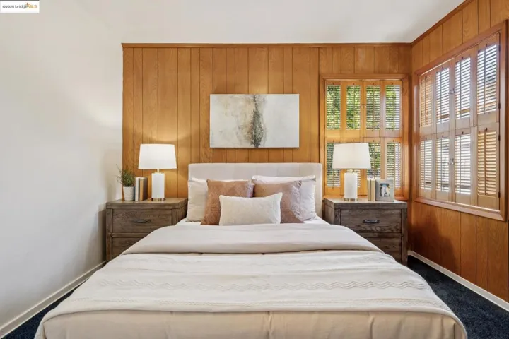 Carpeted bedroom featuring wooden walls and baseboards