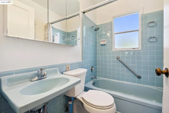Full bath featuring shower / tub combo and tile walls