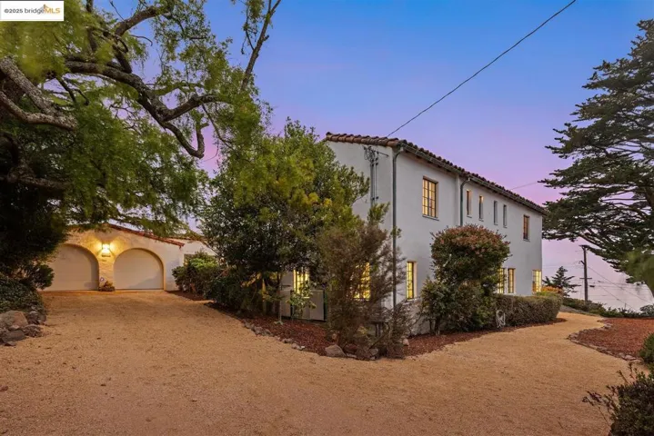 View of front of property featuring a garage, stucco siding, a tiled roof, and driveway
