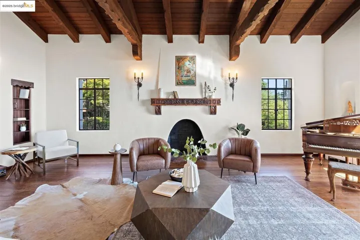 Living area with a wood ceiling with exposed beams, wood finished floors, and a large fireplace