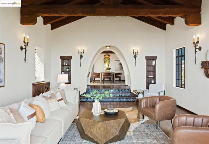 Living room with wood finished floors, beam ceiling, and high vaulted ceiling