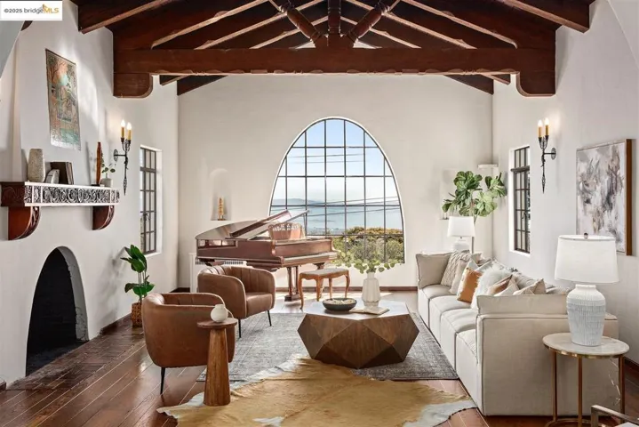 Sitting room featuring a water view, beamed ceiling, wood-type flooring, high vaulted ceiling, and a fireplace