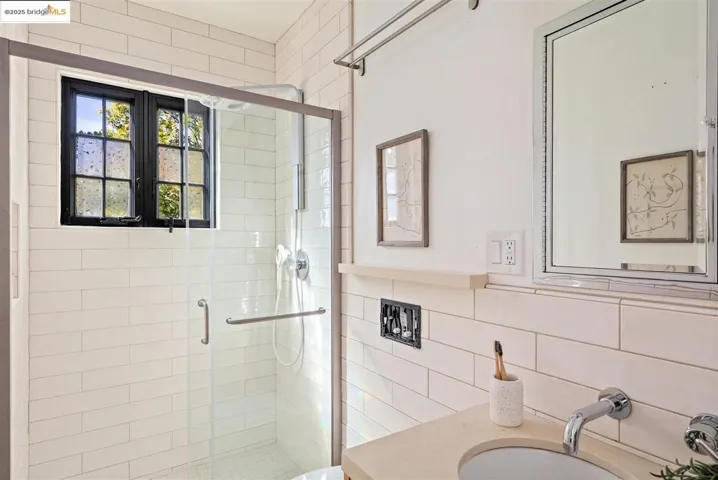Full bathroom with a shower stall, backsplash, vanity, and tile walls