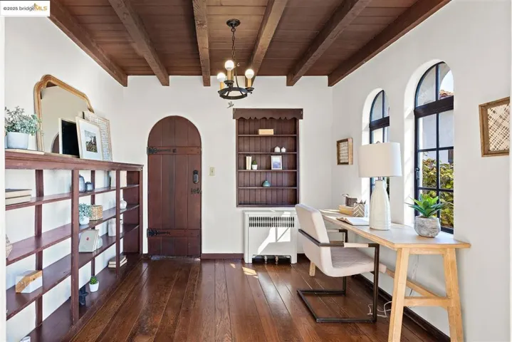 Office area with radiator, dark wood-style floors, arched walkways, and a chandelier