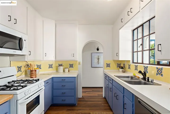 Kitchen with blue cabinetry, white appliances, and white cabinets