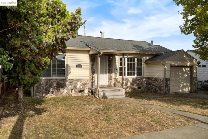 View of front of house featuring stone siding, roof with shingles, and an attached garage