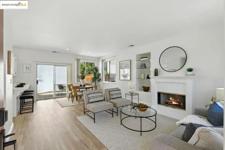Living area with a tiled fireplace, light wood finished floors, and built in shelves