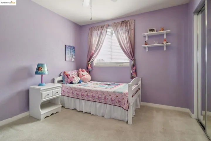 Bedroom with light colored carpet, a closet, and a ceiling fan