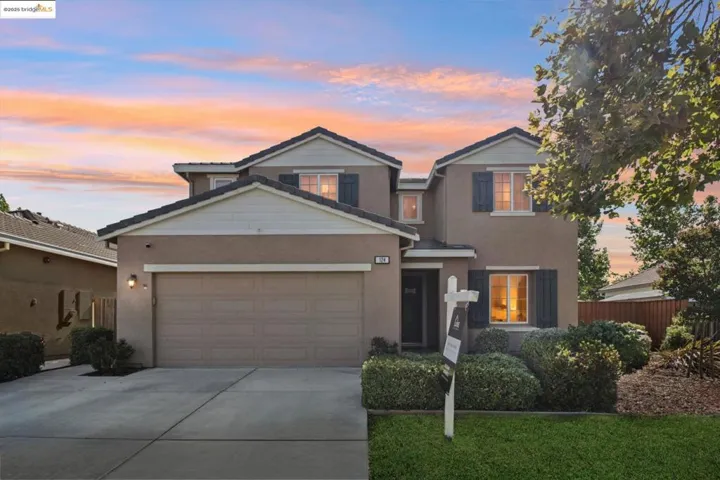 Traditional-style home featuring driveway, a garage, and stucco siding