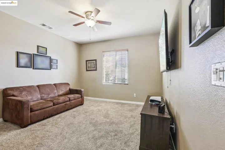 Living room featuring light colored carpet and a ceiling fan