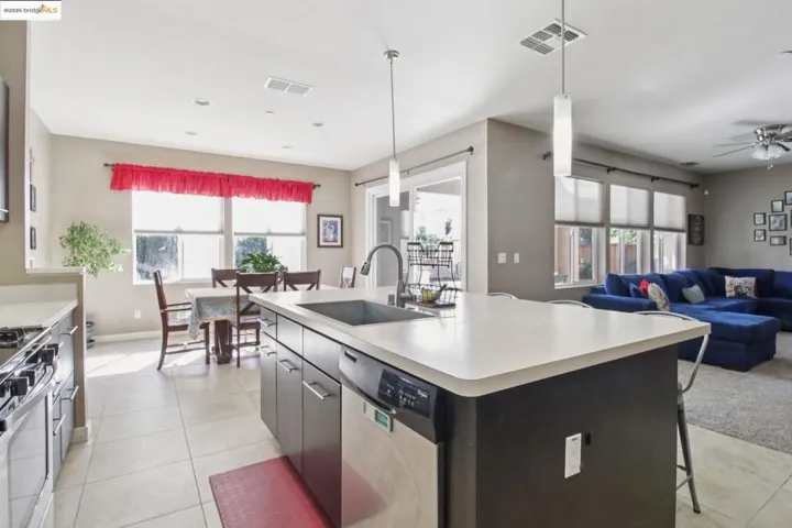 Kitchen featuring light countertops, a center island with sink, pendant lighting, and appliances with stainless steel finishes