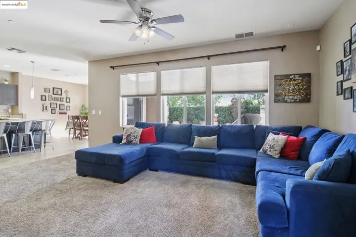 Living area featuring light colored carpet and a ceiling fan
