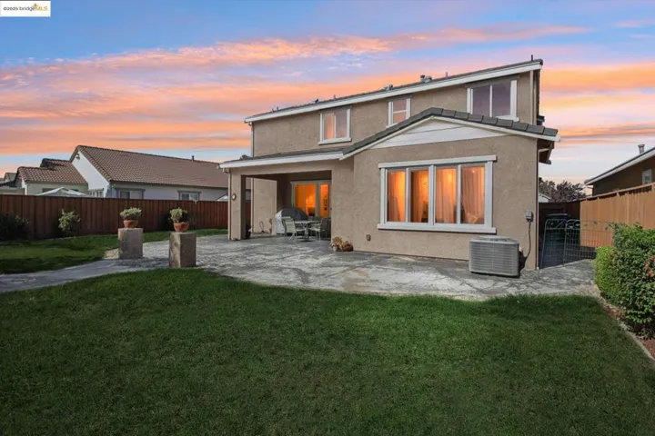 Back of house at dusk with stucco siding, a patio area, and a fenced backyard