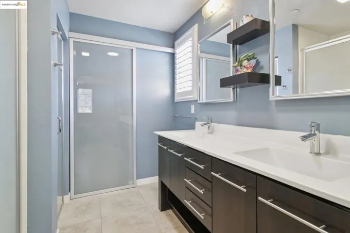 Full bathroom featuring a stall shower, light tile patterned floors, and double vanity