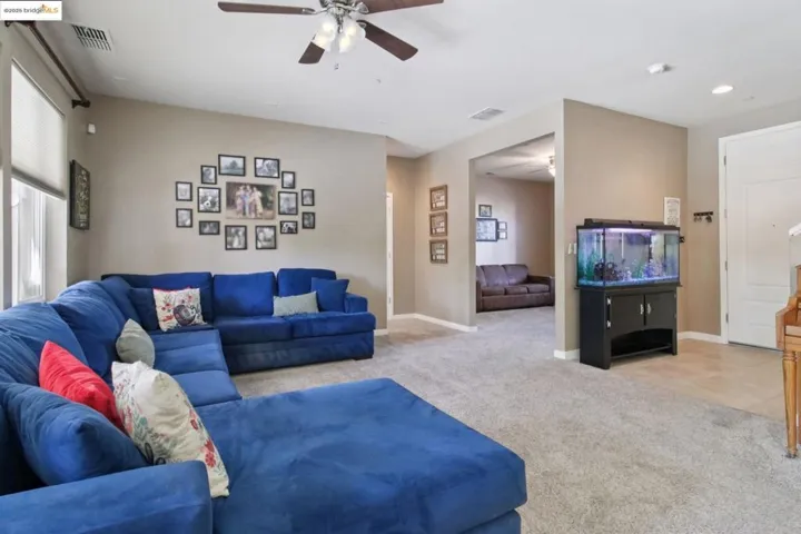 Living area featuring light carpet, ceiling fan, and recessed lighting