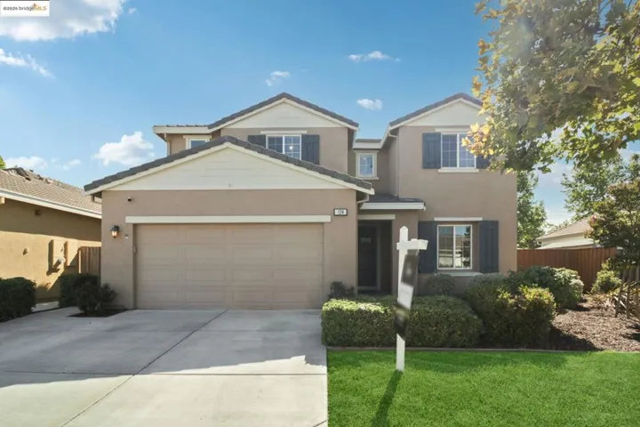 Traditional-style home featuring an attached garage, driveway, and stucco siding