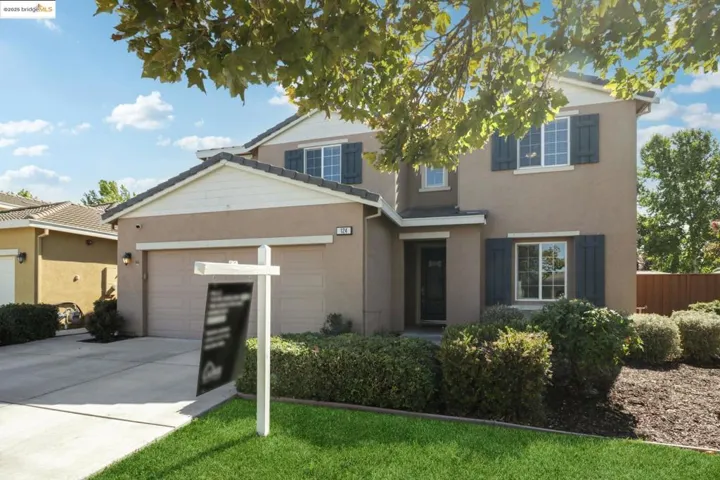 Traditional-style house featuring concrete driveway, stucco siding, a garage, and a front lawn