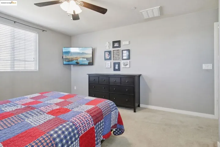 Bedroom with light carpet and a ceiling fan