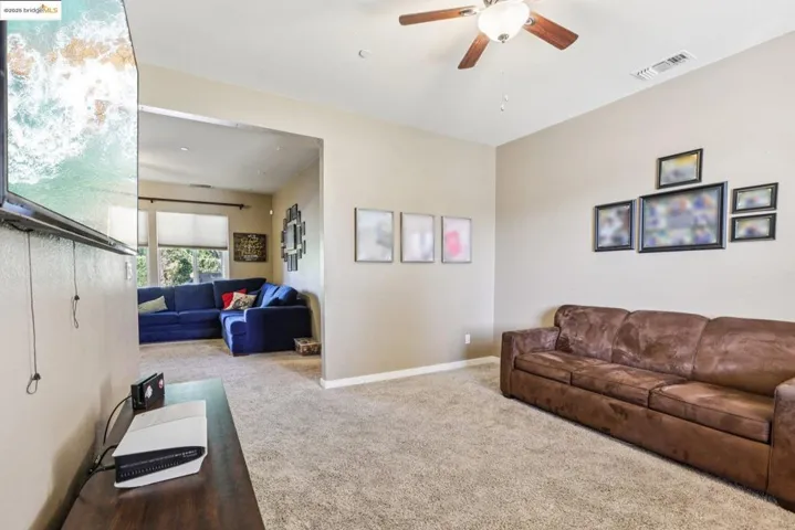Carpeted living room with ceiling fan and baseboards