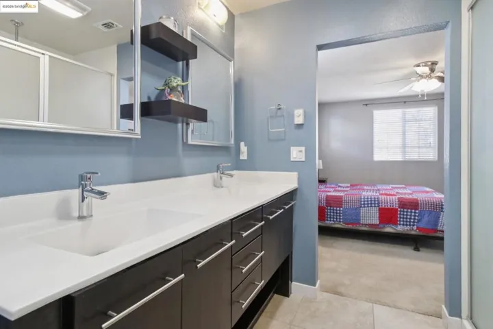 Bathroom featuring double vanity, connected bathroom, a shower stall, a ceiling fan, and light tile patterned floors