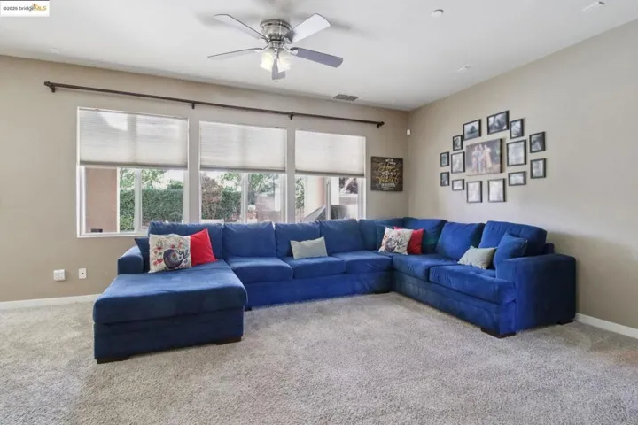 Carpeted living area with baseboards and ceiling fan