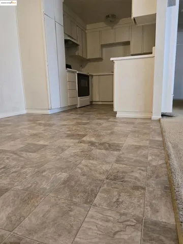 Kitchen with range with electric cooktop, under cabinet range hood, and a heating unit