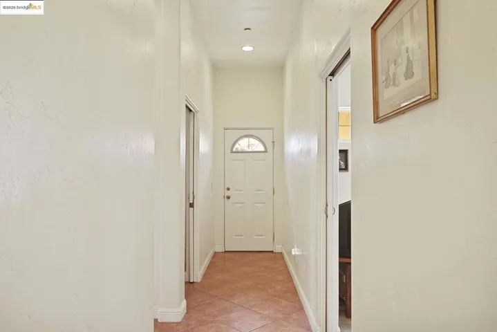 Hall with light tile patterned flooring and baseboards