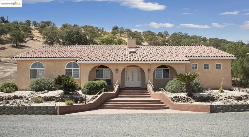 Mediterranean / spanish home with stucco siding, a chimney, a porch, and a tile roof