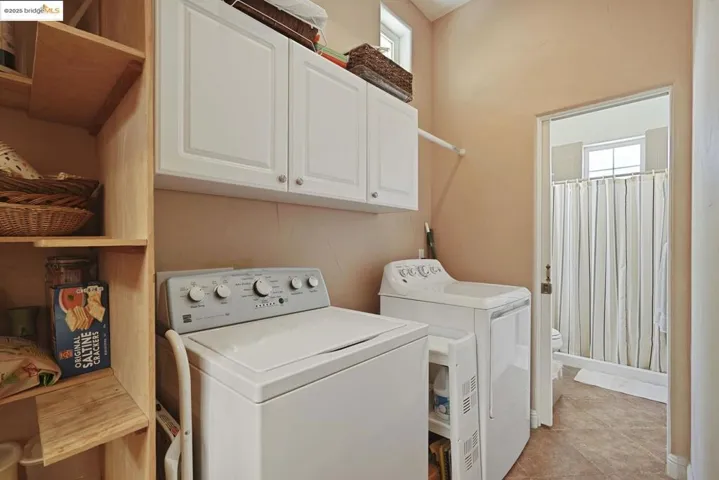 Laundry room with healthy amount of natural light, light tile patterned floors, cabinet space, and washer and dryer