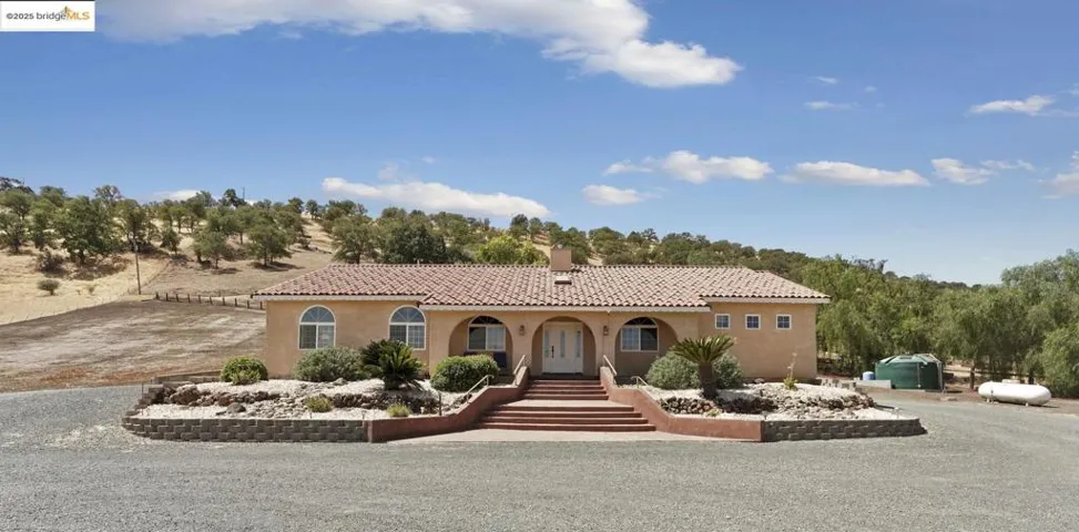 Mediterranean / spanish home featuring stucco siding, a tiled roof, a chimney, and a porch