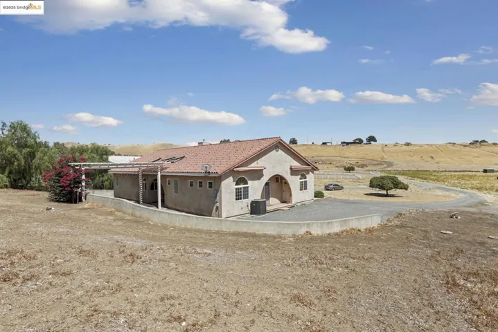 Rear view of house with a tile roof, stucco siding, and a patio