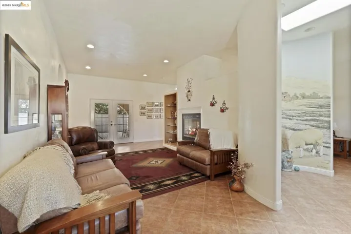 Living area featuring light tile patterned floors, recessed lighting, and french doors