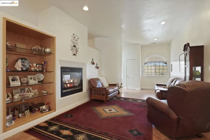 Living area featuring a multi sided fireplace, light tile patterned flooring, and recessed lighting