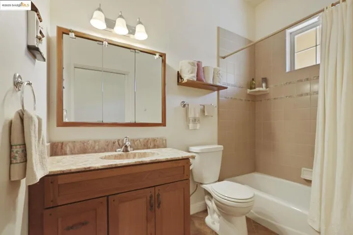 Full bath with shower / bathtub combination with curtain, vanity, and light tile patterned flooring
