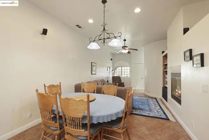 Tiled dining room featuring a glass covered fireplace, recessed lighting, and built in shelves