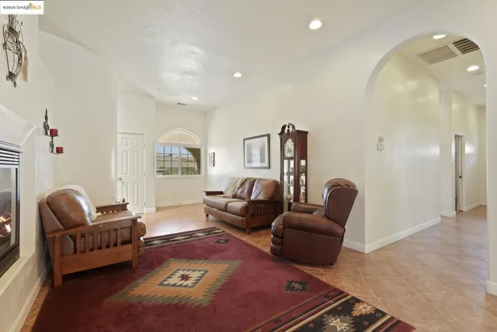 Living room featuring light tile patterned floors, arched walkways, and recessed lighting