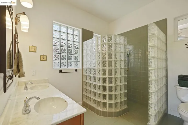 Full bath with walk in shower, tile patterned floors, and double vanity