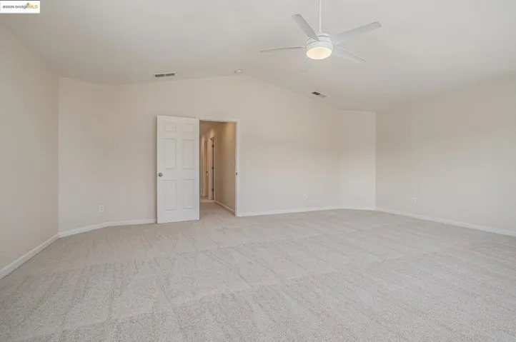 Featuring vaulted ceiling, light carpet, and a ceiling fan