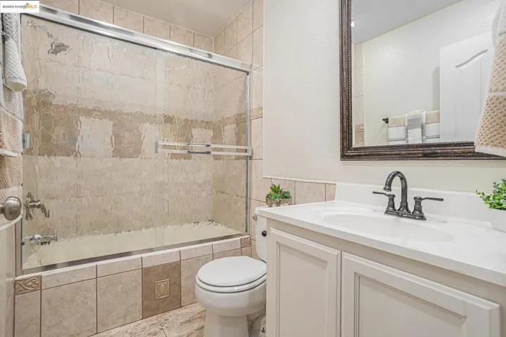Bathroom featuring tiled shower / bath combo, vanity, tile patterned flooring, and white cabinet.