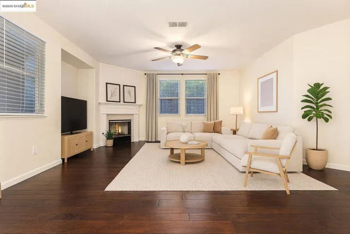 Living area featuring a ceiling fan, dark wood finished floors, and a glass covered fireplace