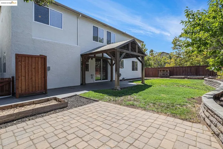 Rear view of house featuring a patio, stucco siding, a fenced backyard, and a gazebo.
