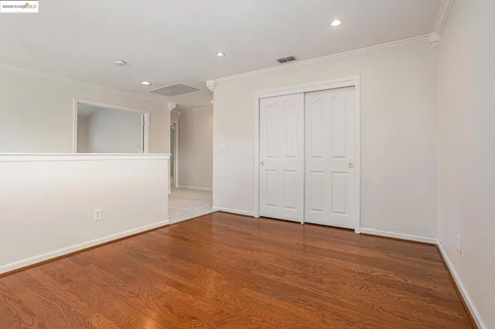 Loft or optional bedroom with closet, featuring crown molding, recessed lighting, and wood floors