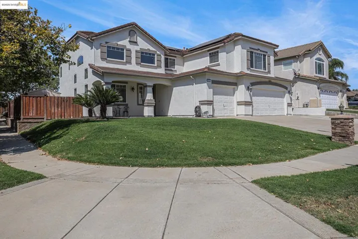 View of front of house with concrete driveway, a garage, stucco siding, and roof mounted solar panels