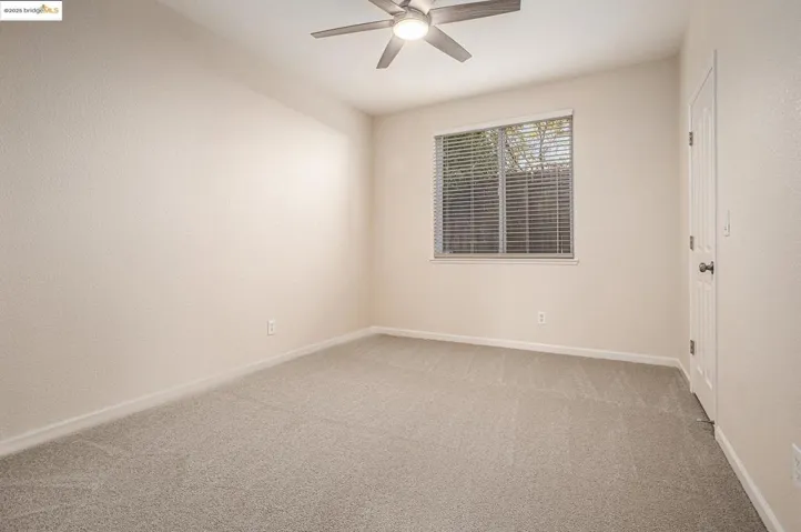 Bedroom 2/spare room- On the lower level, featuring light colored carpet, ceiling fan, and walk-in closet organizer.