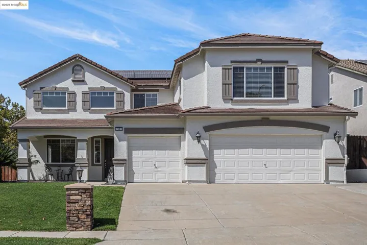 View of front of house with a tiled roof, roof mounted solar panels, concrete driveway, and stucco siding