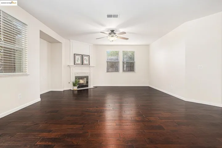 Living room featuring a ceiling fan, engineer hardwood flooring, and a fireplace with flush hearth.