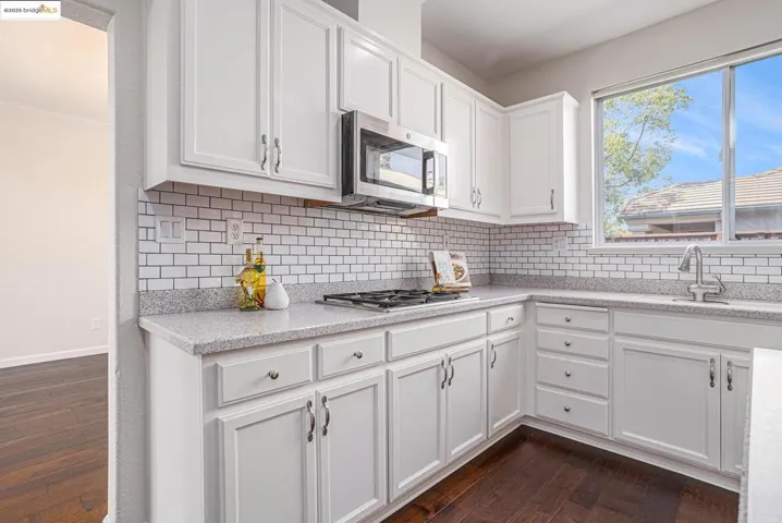 Kitchen featuring white cabinetry, stainless steel appliances, and tasteful backsplash.