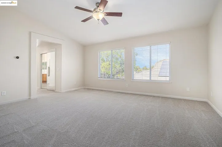 Featuring light carpet, vaulted ceiling, new vinyl blinds and a ceiling fan