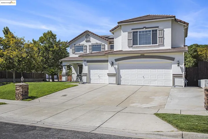 Traditional-style home with a tiled roof, an attached garage, solar panels, stucco siding, and driveway